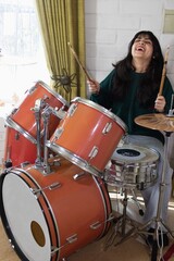 latina teenage girl playing drums at home
