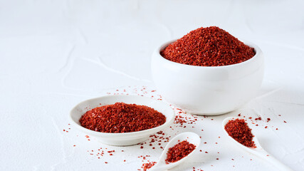 closeup Korean red chili pepper flake, ground powder coarse paprika or Gochugaru on white table background in spoon and bowl with copy space