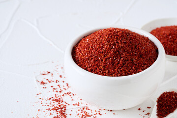 closeup Korean red chili pepper flake, ground powder coarse paprika or Gochugaru on white table...