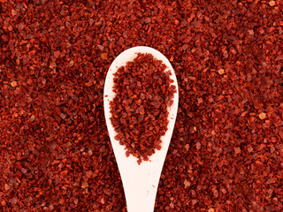 flat lay Korean red chili pepper flake, ground powder coarse paprika in white spoon on food red Gochugaru background