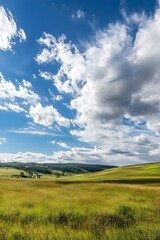 Obraz premium Rolling green hills under a blue sky with fluffy clouds