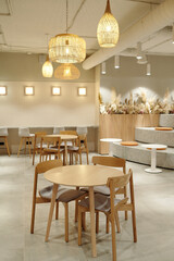 Modern coworking space featuring empty wooden tables and chairs, bar stools along counter, decorative pendant lights, tiered seating area
