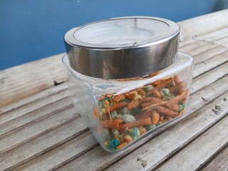 A mix of snacks during Eid such as Bogor peanuts, which taste savory and salty, in a jar on a bamboo chair