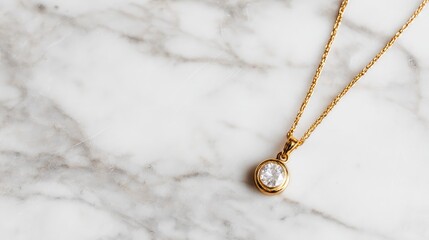 Fototapeta premium Gold chain with small diamond pendant on a clean white marble surface