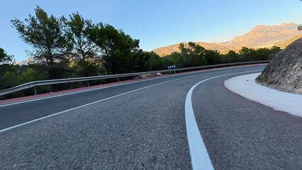 Fototapeta premium A winding road winds through majestic mountains, lush greenery, and clear blue skies, ideal for adventurers