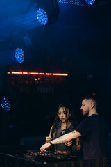 Two DJs Collaborating in a Club with Vibrant Lighting