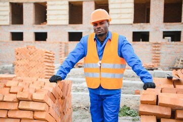 African american construction worker. Portrait of mason bricklayer installing red brick with trowel...