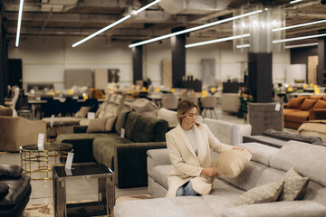 Woman Evaluating Sofas and Cushions in a Stylish and Modern Furniture Store