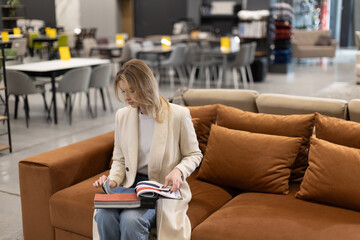 Woman Browsing Furniture Catalog on a Couch in a Store Showroom