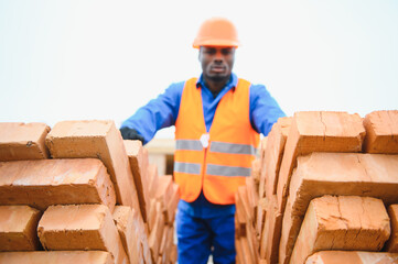 African american construction worker. Portrait of mason bricklayer installing red brick with trowel...