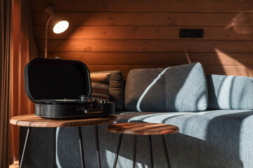 Turntable on a wooden coffee table in a cozy living room with soft lighting, striped pillow on a...
