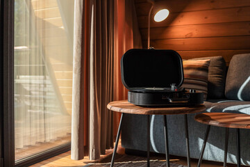 Turntable on a wooden coffee table in a cozy living room with soft lighting, striped pillow on a...