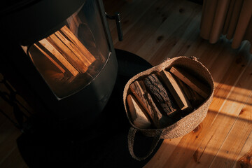 Top-down view of a cozy interior with a black wood-burning stove and a wicker basket full of...