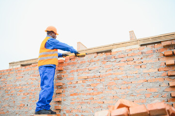 African american construction worker. Portrait of mason bricklayer installing red brick with trowel...