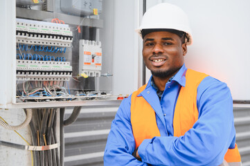 Joyful african american electrician mounting electric switchboard outdoors
