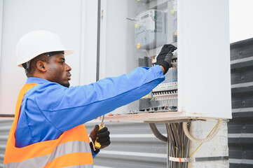 Joyful african american electrician mounting electric switchboard outdoors