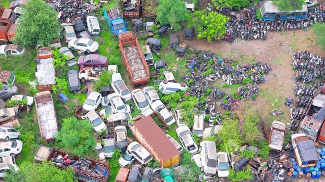 Drone shot wrecked trucks and oxidized cars in scrapyard