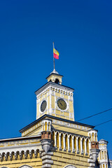 Moldovan flag is fixed on clock tower of old municipality building. Moldovan flag on blue sky background. Chisinau, Moldova.  Copy space. Selective focus.