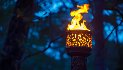Captivating flame dances atop a decorative torch illuminated at night in a forest setting