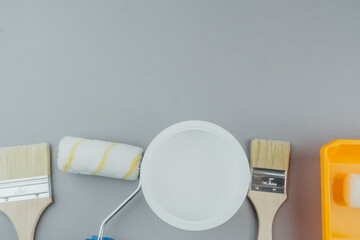 Top view of paint bucket and tools including rollers and brushes for interior renovation and home painting concept