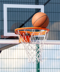 A basketball is sitting on top of a basketball net