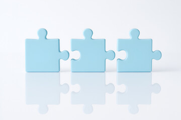 Three blue puzzle pieces on a white reflective surface