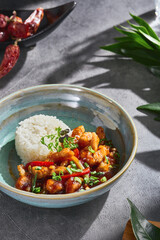Kung pao chicken in sweet and sour sauce with steamed rice, bright natural lighting, overhead composition
