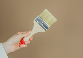 Single paintbrush in hand on brown background for simplicity and tool presentation concept