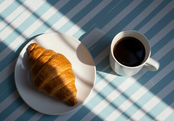 Croissant and Black Coffee on Striped Table in Sunlight