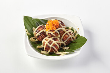 Crispy takoyaki balls topped with creamy mayonnaise, savory sauce, and fish roe, served on banana...