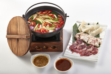Traditional Thai hot pot featuring Tom Yum soup with vibrant ingredients like lemongrass, chili,...