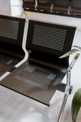 Empty metal bench seats in a public waiting area, minimalistic interior, polished floor, and wooden...