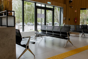 Empty metal bench seats in a public waiting area, minimalistic interior, polished floor, and wooden...