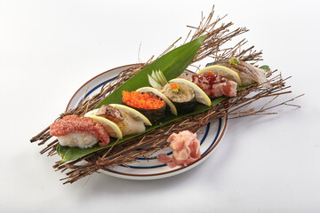 Beautifully arranged sushi platter featuring variety of fresh sushi pieces, including fish roe, tuna, and other seafood, served on decorative plate with garnishes like ginger and lemon slices