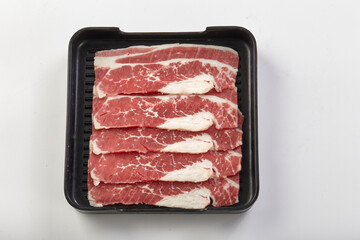 Thinly sliced fresh beef arranged neatly in black tray, showcasing marbled fat and vibrant red meat, perfect for hot pot or grilling