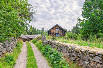 Idyllic rural landscape with a dirt road between stone walls to an old farm