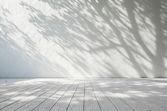 Abstract natural light and shadow patterns cast by tree branches on a textured white wall and wooden floor