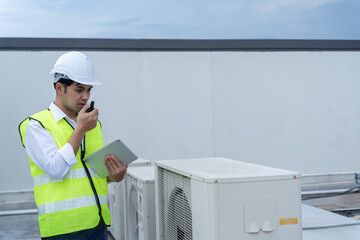 Asian maintenance engineer works on the roof of factory. contractor inspect compressor system and...