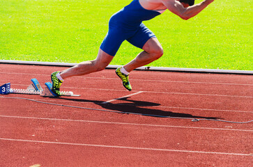 Sprinter launching from starting blocks, muscular athlete immediately after the gunshot in action photo