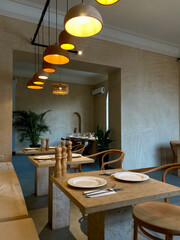Modern minimalist restaurant interior with natural textures, pendant lighting and set tables
