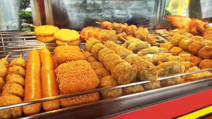 Thai street food Variety in nightmarket: A mouthwatering spread of diverse, deep fried delicacies at a food stand, a tempting treat. The food items are in a warm light, ready to be enjoyed.