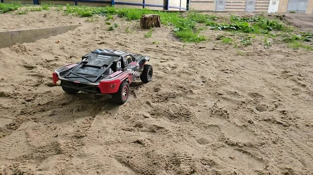 MOSCOW - JUN 12, 2024: Red toy car is on the sand. The car is on the ground drift slow motion