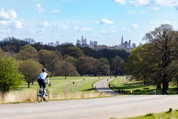 Cyclist in south west London heads to the stunning backdrop of Central London skyscrapers in spring