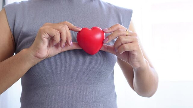 woman’s hand holding a red heart shaped object, symbolizing heart health awareness, the importance of early checkups, heart care, and reminders for World Heart Day and cardiology support
