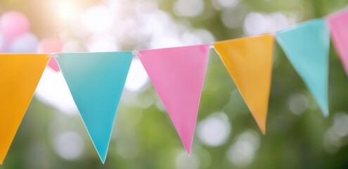 Colorful festive pennant flags in sunlit outdoor setting with blurred green background