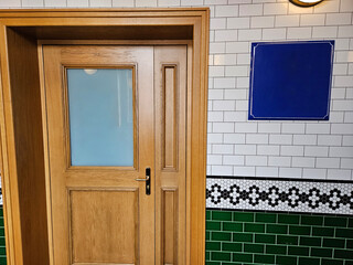 Wooden door and ceramic tile wall. The sign is blue