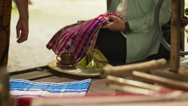 Close-Up of Hands Examining a Silk Sarong, Then Receiving Traditional Bugis-Makassar Snacks and Tea &ndash; Cultural Hospitality Moment