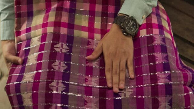 Close-Up of a Hand Gently Stroking a Purple Silk Sarong &ndash; Appreciation of Traditional Indonesian Fabric