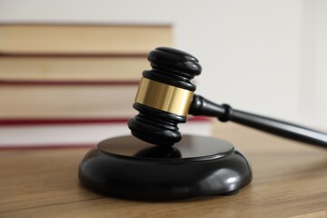 Judge's gavel and books on wooden table indoors, selective focus