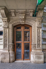 Obraz premium Historic 1900 Building Entrance With Elaborate Stone Carvings And Wooden Doors In Barcelona. Art Nouveau Architecture, Ornate Facade, Decorative Columns, Modernist Style, Heritage Building
